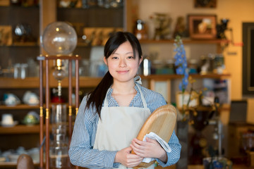 お盆を持ち微笑むカフェの店員
