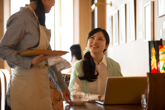 カフェの店員と談笑をする女性