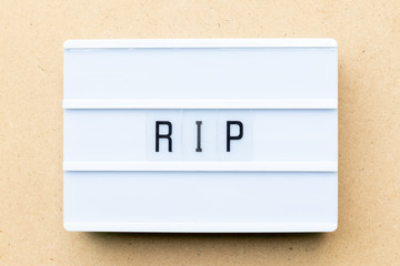 White lightbox with word RIP (abbreviation of rest in peace) on wood background