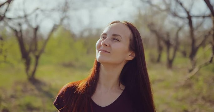 Beautiful young woman walking on a sunny day and smiling. Spring nature. Portrait view.