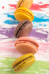 Lots of macarons colored on a color watercolor bright background. Confectionery art concept. Delicious megaltic cookies