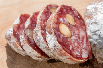 Dried sausage with nuts cut in slices close-up view on a wooden table