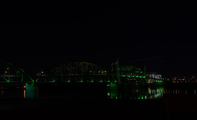 Bridge with colorful lighting at night and park bench in foreground