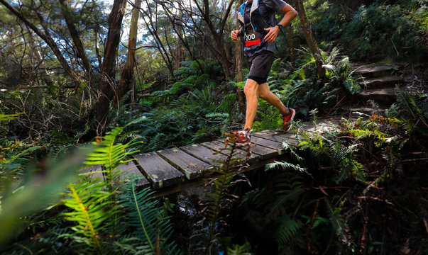 male running over a wooden bridge as part of an Ultra trail running event