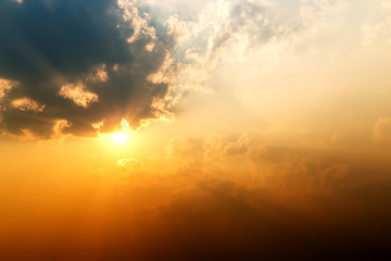 Orange sunrise over clouds with bright yellow sun on a cool spring morning.