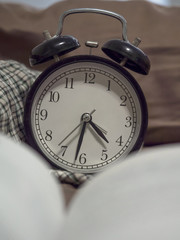 Vintage alarm clock and book on vintage bed