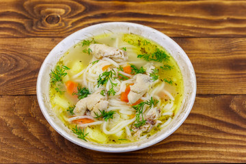 Chicken soup with noodles and vegetables on wooden table