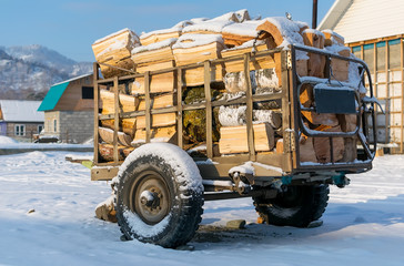 Obraz premium Cart, trailer, wagon for transportation of firewood is for sale in the countryside in the snow in winter
