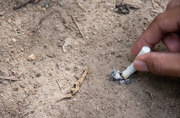 Men smoke in the park. The tobacco handle extinguishes the fire with soil.