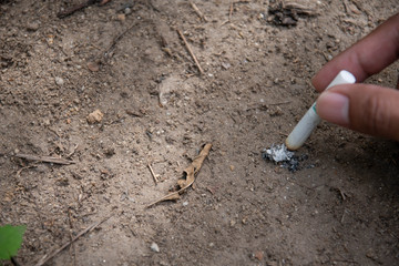 Men smoke in the park. The tobacco handle extinguishes the fire with soil.