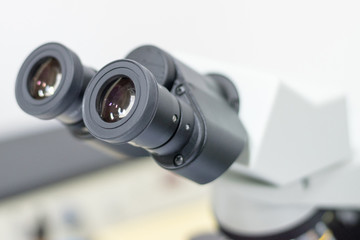 Medical healthcare concept. Ocular eyepiece lenses and tube of binocular microscope for lab technician in laboratory research in hospital or university with white copyspace.Science Education Day