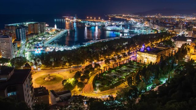 Aerial view of port, buildings and city lights reflecting in ocean, Malaga Spain