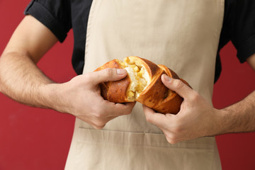 Baker with fresh bread on color background, closeup