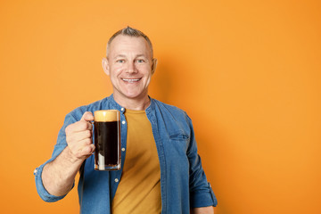 Happy middle-aged man with glass of beer on color background