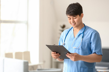 Male medical assistant with clipboard in clinic