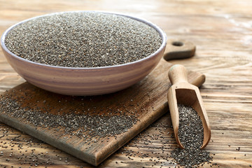 Scoop and bowl with chia seeds on wooden table