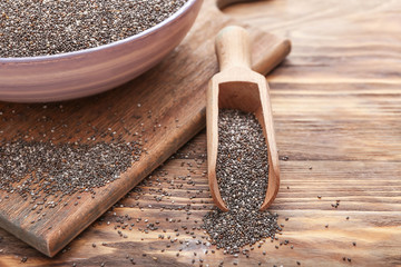 Scoop and bowl with chia seeds on wooden table