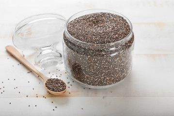 Spoon and jar with chia seeds on table