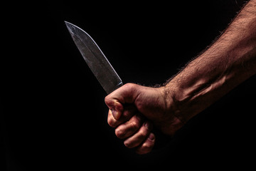 Hunting knife in hand on dark background