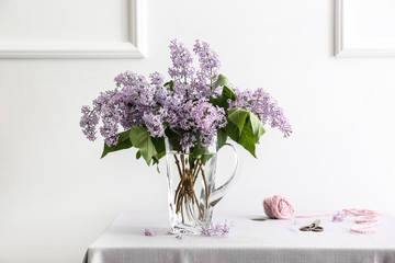 Vase with beautiful lilac flowers on table in room