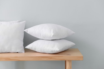 Fototapeta na wymiar Soft pillows on table against light wall