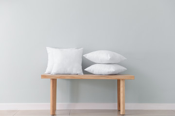 Fototapeta na wymiar Soft pillows on table against light wall