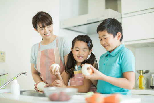 キッチンで玉ねぎの皮を剥く母親と子供たち