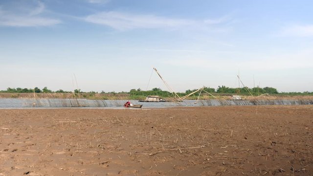 woman sitting in a fishing boat and sorting river clams harvested. House boat as backdrop.  (zoom in )