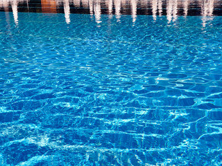 Fototapeta na wymiar Throbbing blue pool water with sun reflections 