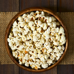 Homemade fresh savory popcorn with cheese, garlic and dried oregano in wooden bowl, photographed...