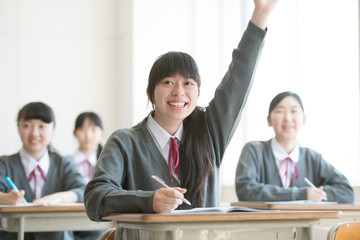 教室で手を挙げる女子学生