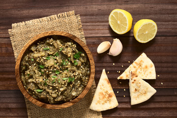 Frischer Auberginen-Dip oder Aufstrich, Baba Ghanoush in der Arabischen Küche, mit Sesam, Petersilie und Olivenöl in Holzschüssel serviert, Pita Chips an der Seite, fotografiert mit natürlichem Licht 
