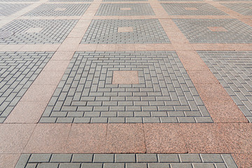 Combining concrete and granite tiles in paving. Square geometric ornament.