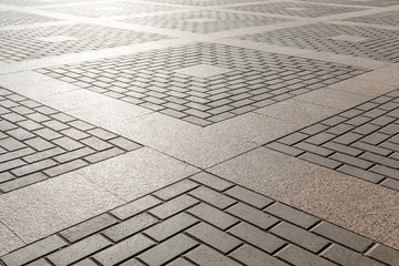 Combining concrete and granite tiles in paving. Square geometric ornament.