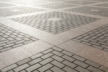 Combining concrete and granite tiles in paving. Square geometric ornament.