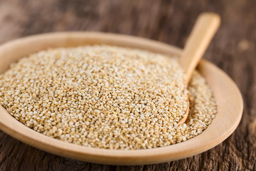 Rohe weiße Quinoa Samen (lat. Chenopodim quinoa) auf Holzteller (Selektiver Fokus, Fokus ein Drittel in die Quinoa)