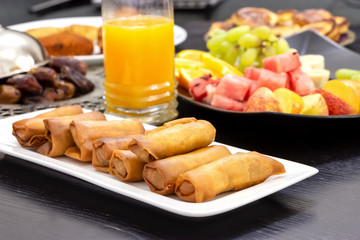 Iftar buffet table. Spring roll, fruits, fresh orange juice, samosa snack, spring roll and pancake background concept iftar holy month Ramadan.