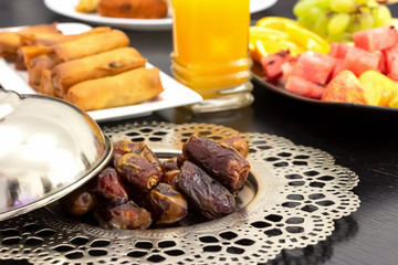 Dried dates palm fruits, fresh orange juice, samosa snack and fruit background concept iftar in the holy month Ramadan.