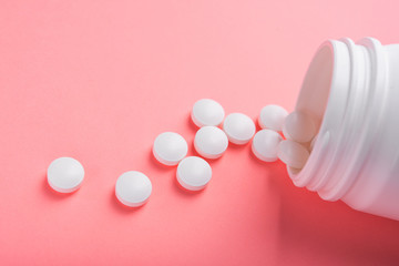Closeup of white pills on a pastel pink color background