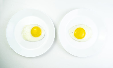 traditional breakfast of two fried eggs. White plate with eggs on the background of a white wooden table. Concept image of breakfast, healthy eating.