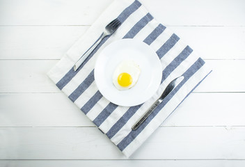 traditional breakfast of two fried eggs. White plate with eggs on the background of a white wooden...
