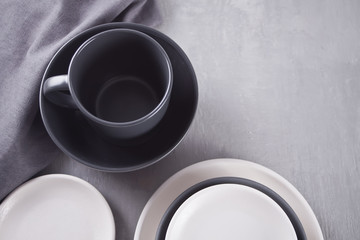 Empty black and white plates over gray table.
