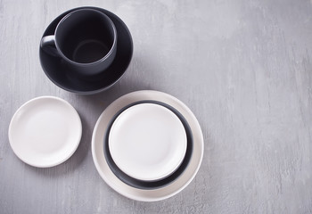 Empty black and white plates over gray table.