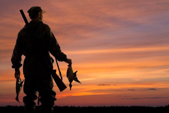 duck hunter with prey at sunset