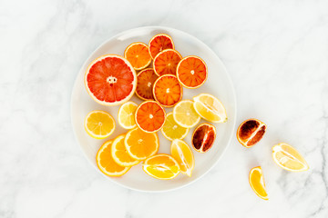 Arrangement of Cut Oranges, Blood Oranges, Lemon and Grapefruit on White Plate