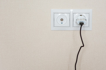 The phone cord is plugged into the outlet for charging.