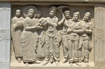 View of stone carved wall art of Buddha receiving  water from the king on the stupa, in Mahabodhi Vihara or temple and monastery