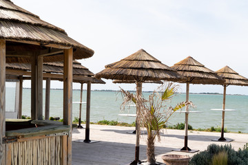 wood bamboo hut as a bar straw roof on beach and many straw parasol in panoramic view