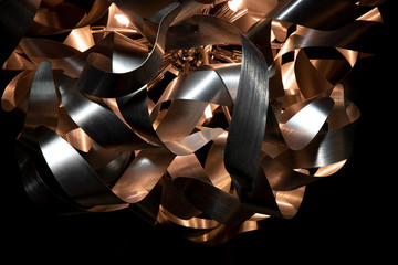Silver and copper metal curved metal ribbon chandelier closeup. Modern metal lampshade.