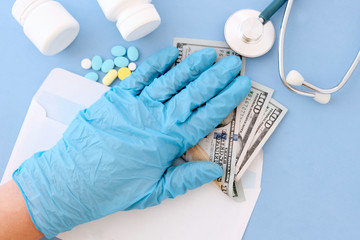 Dollars in the hands of a doctor in blue medical gloves. The view from the top. The doctor receives a salary, bribes, corruption concepts.